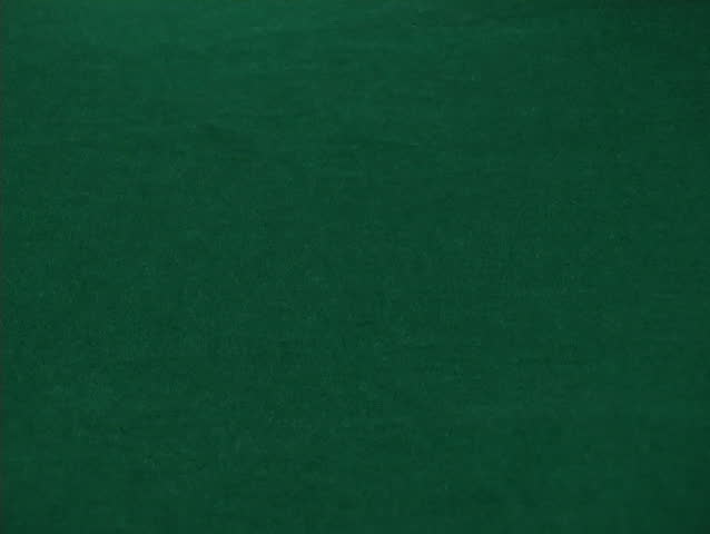 Poker chips tumble onto a green felt table in a casino.