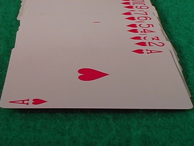 A flyover shot of a full deck of cards on a green felt table.