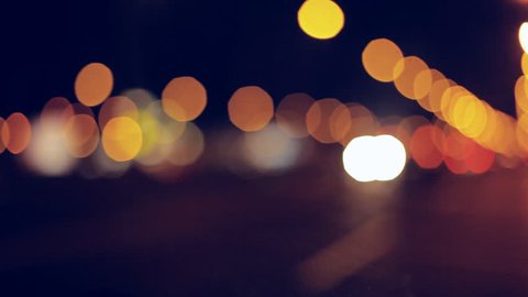 Driving at night. Windshield view and blurred cars in city. Illuminated front car window with blurred city traffic on town streets.