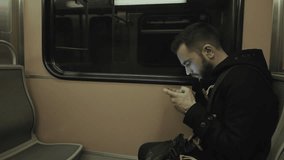 Young man traveling by train/subway playing and passing time on tablet.HD clip of a young man using his tablet while commuting on the metro train.Train arriving to the destination/station.