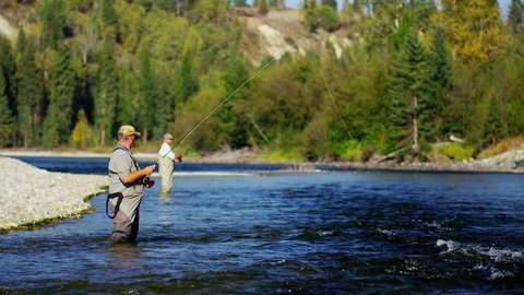 Fisherman using rod and reel fly fishing in freshwater river USA