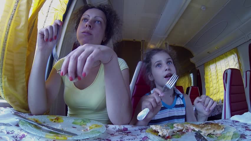 Mother and her daughter eat near window in train restaurant during ride. Action camera shot