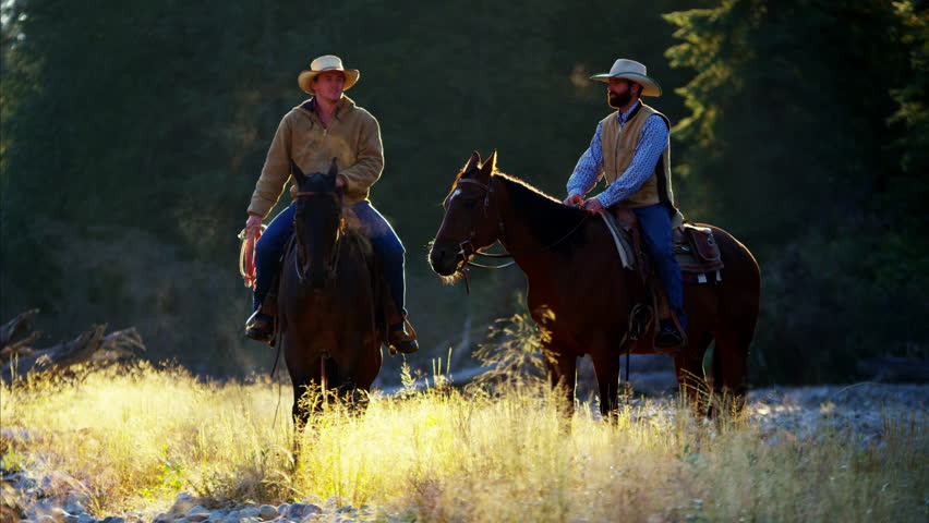 Cowboys Riding horses in the river wilderness area Canada