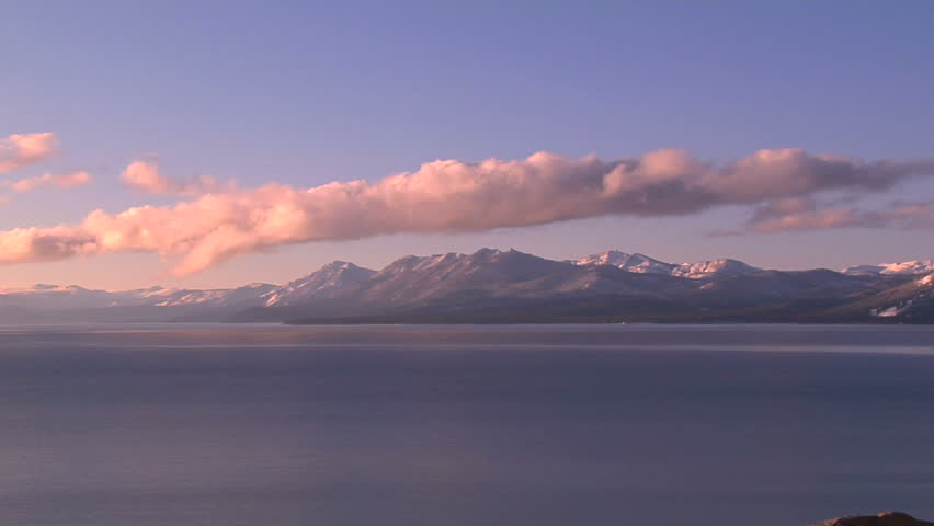 Pink Sunlit Clouds Rolling Over Lake Tahoe and Surrounding Snow Capped Mountains, Timelapse