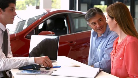 Customers sigining some important documents at the car showroom