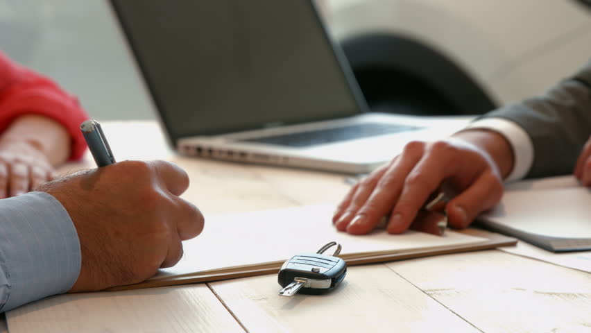 Businessman siging some documents at the car showroom