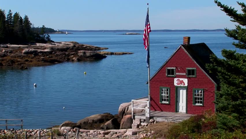 A red house sits on the edge of a bay at a lobster village in Stonington, Maine.