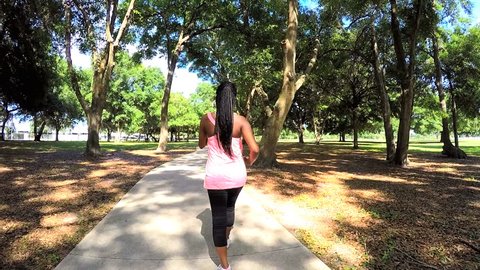 Young active African American fitness female enjoying power walking in park
