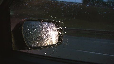 Rainy highway mirror.  View of passenger mirror through wet side window. Highway 401, Ontario, Canada. 