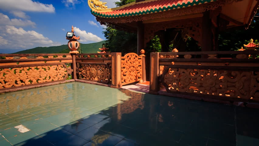 european tourist in straw hat with back bag comes to barrier passing by pagoda looks at picturesque age-old monastery