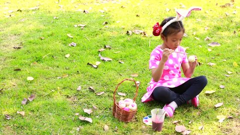 Little girl painting egg preparing for Easter celebration