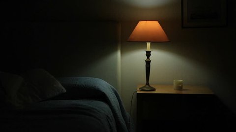 Man prepares to go to bed and sleep. Person lays down in bed and turns off night stand besides bed