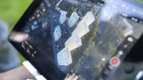Screen of tablet quadrocopters remote control with image of housing complex from top on it.