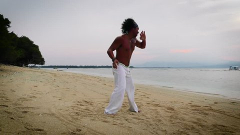 Brazilian capoeira dancer training on the beach at sunrise.
