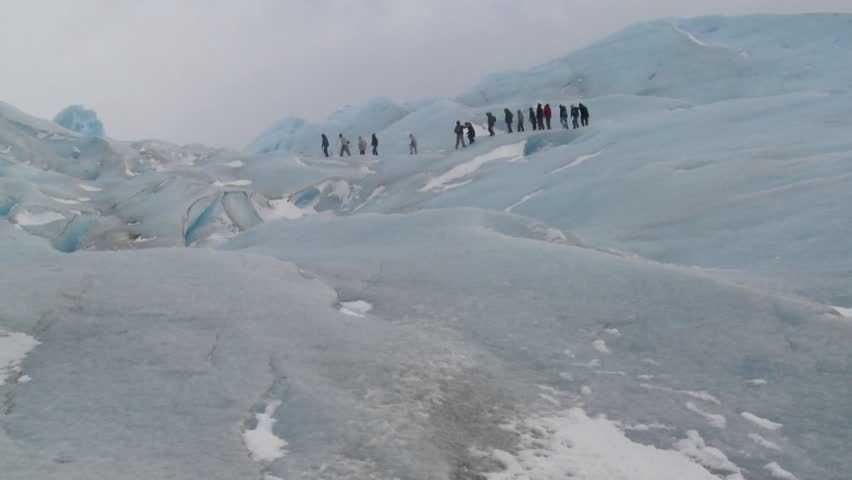 A group of explorers move across a glacier.