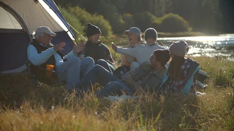 Multi generation family relaxing outside tent in countryside