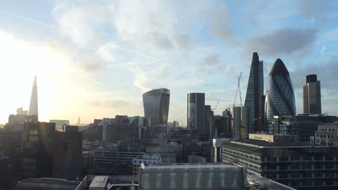 Time lapse video of the City of London financial district on a sunny day. The Shard, Walk-ie Talkie, Cheese Grater, and Gherkin buildings. Sun and clouds with aircraft contrails.