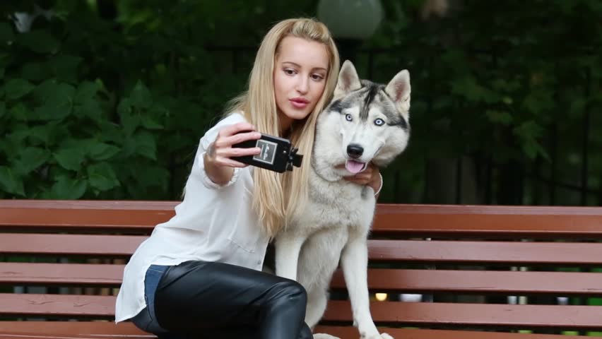 Young woman with dog Husky doing selfie on bench in park. Royalty-Free Stock Footage #14763346