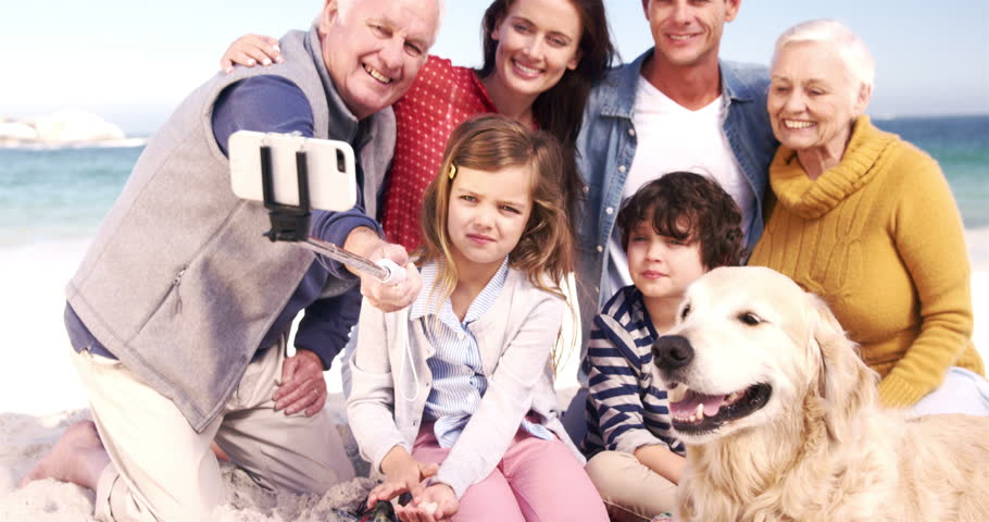 Three generations family with dog taking selfie on the beach