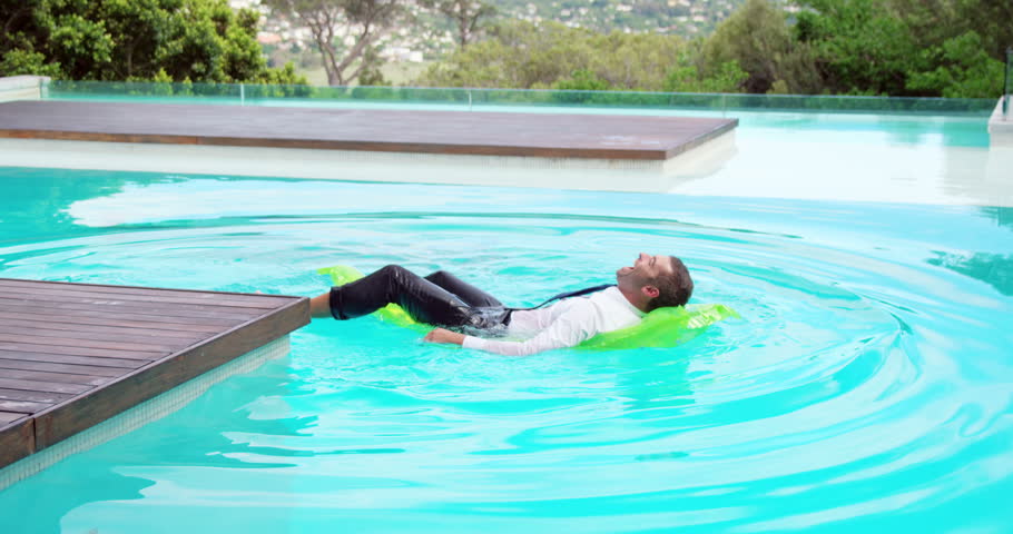 Businessman lying on lilo in swimming pool