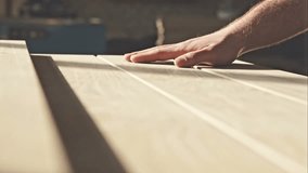 The young master hand touches the wooden boards in the sun. RAW video record.