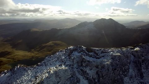Aerial shot circling Crib Goch, Snowdonia, UK. Lakes visible initially, then Mount Snowdon comes into view at the end of the shot.