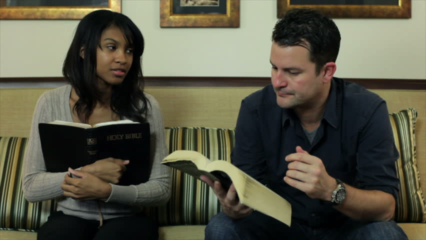 The camera pans from a lovely African American girl and a male friend to a woman engaging them in conversation about what they are studying in their Bibles.