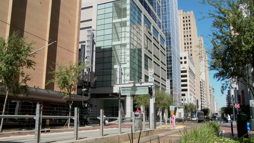 A rapid transit train moves quickly through downtown Houston with fountains dancing.