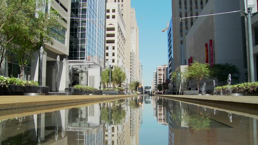 A rapid transit train moves quickly through downtown Houston with fountains dancing.