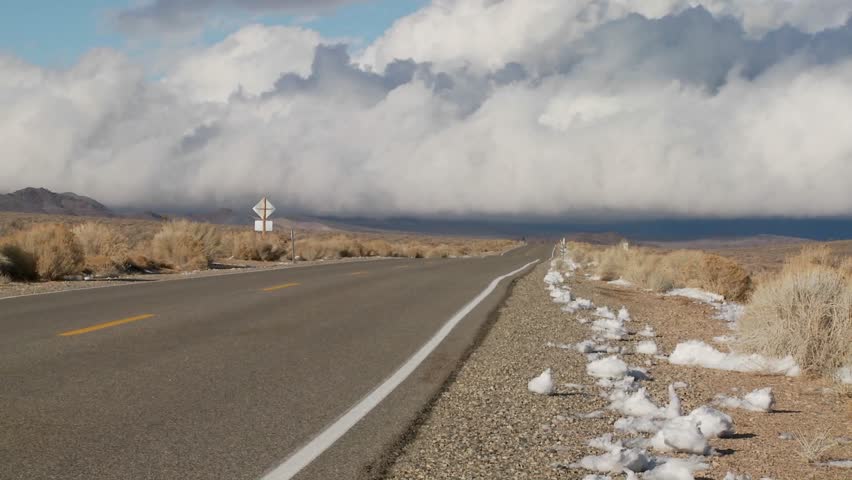 Clouds form over a remote desert road.
