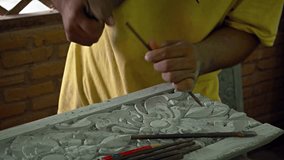 Cambodian artisan. chipping intricate. ornate details into a stone slab using a traditional hand chisel and mallet in his Siem Reap workshop. UHD video