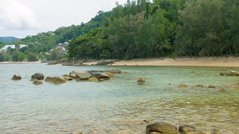 Natural tree line backs a beautiful. sandy. tropical beach near a luxury resort complex on the island of Phuket in Thailand. Video 3840x2160