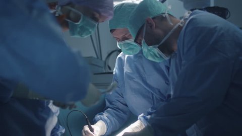 Medical Team Performing Surgical Operation in Modern Operating Room. Shot on RED Cinema Camera. Video Stok