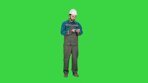 Construction worker using cell phone to send message on a Green Screen, Chroma Key.