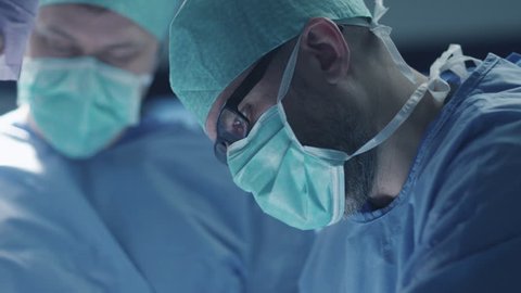 Portrait of Focused and Concentrated Surgeon Performing Surgical Operation in Modern Operating Room. Shot on RED Cinema Camera.