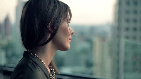 Young, pensive woman admire view from terrace

