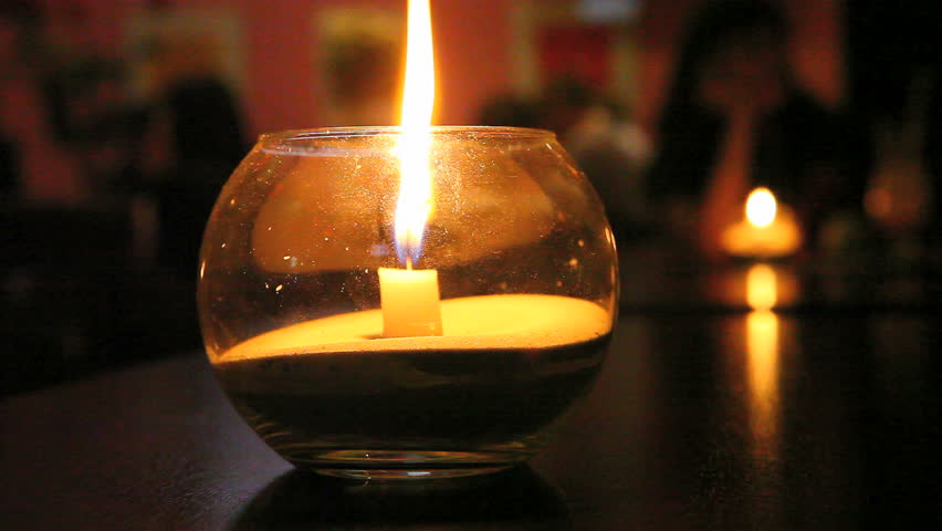 candle burns in a glass vase