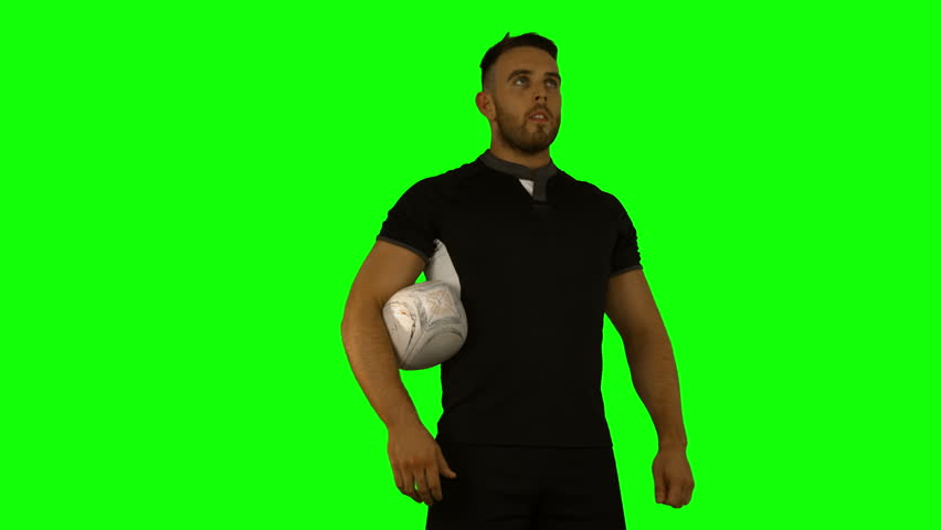 Serious rugby player with ball on green background