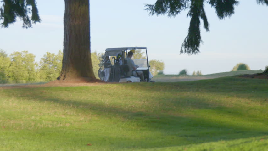Wide shot of two men riding on a golf cart
