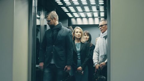 Business people call an elevator, get in when it arrives