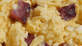 Fried beaten eggs with bacon on plate close-up 4K 2160p 30 fps UltraHD tilting footage - Slow tilt over scrambled eggs with tasty bacon in frying pan 4K 3840X2160  UHD video
