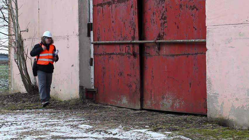 Engineer with tablet PC and documentation near building
