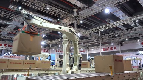 SHANGHAI, CHINA - 7 NOVEMBER 2015: A robotic arm lifts boxes and puts them on a conveyor belt, at a trade show in Shanghai, China