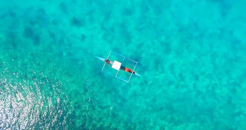 Bird's eye aerial shot of a filipino boat floating on top of beautiful blue waters on Siargao Island, Philippines