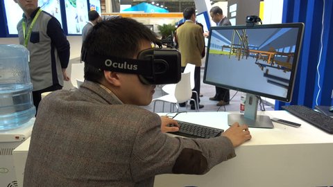SHANGHAI, CHINA - 5 NOVEMBER 2015: A young man uses a virtual reality Ocolus device to walk through a factory (virtually), at a trade show in Shanghai, China