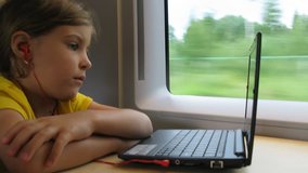 Girl in headphones watch video on notebook while travelling by train, time lapse