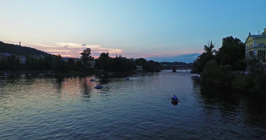 Rising above the Vltava river in Prague, the Czech Republic at sunset. People on boats and a beautiful view of Prague Castle and Prague bridges in 4k. 