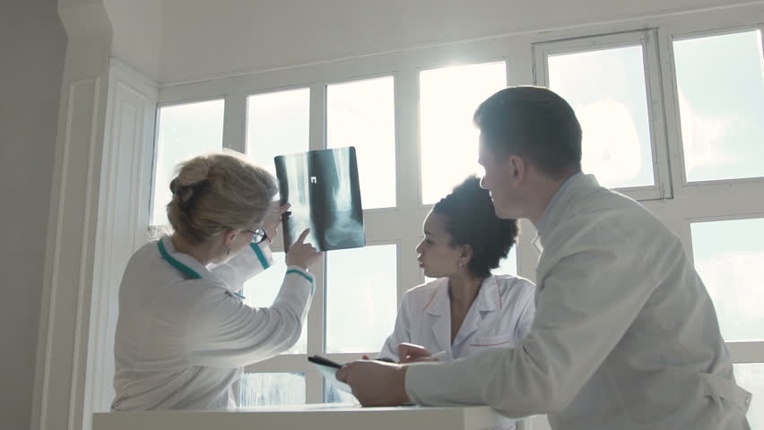 Healthcare, medical: Group of multi-ethnic doctors discuss and looking x-ray in a clinic or hospital. SLOW MOTION