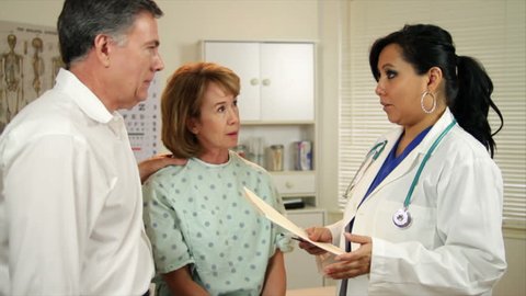 A lovely Hispanic physician discusses her patient's test results with the woman and her husband.