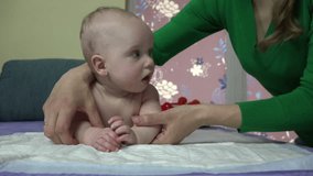 Closeup of tender woman mother carefully exercise little baby boy son hands on bed at home. Woman care newborn health. video clip.